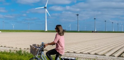 Fietsende vrouw met windmolens in de achtergrond