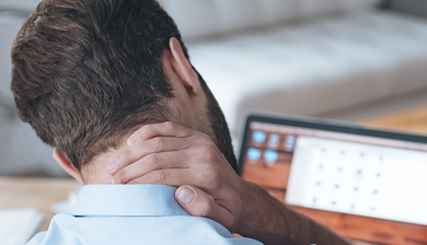 Man met nekpijn achter laptop