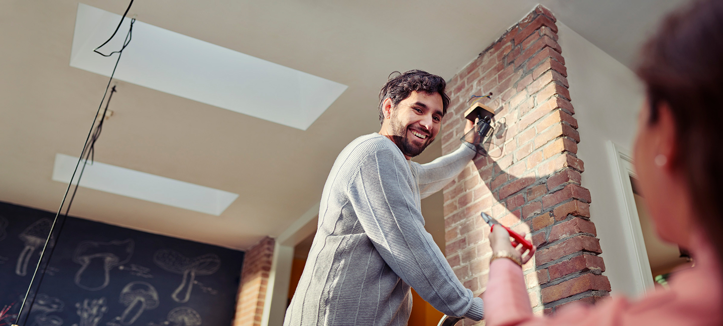 Man hangt lamp op, vrouw geeft gereedschap aan