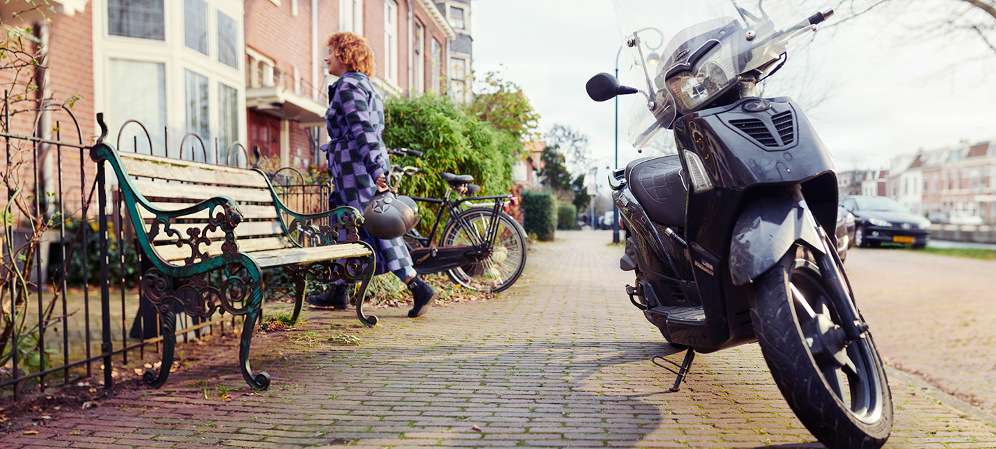 Vrouw loopt naar binnen nadat ze haar brommer heeft geparkeerd