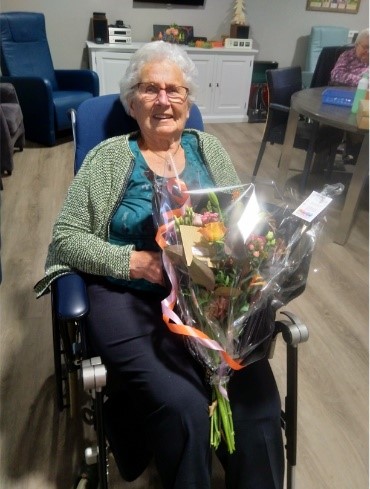 
        mevrouw nikkels met een bos bloemen
      