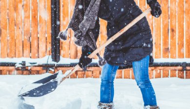 vrouw schept sneeuw weg uit tuin