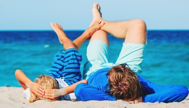 vader en zoon liggen op strand