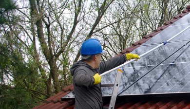 man maakt zonnepanelen schoon